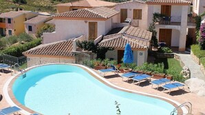 A swimming pool with lounge chairs and a building with a tiled roof. - Crystal Pool Village In Tanaunella (Budoni)