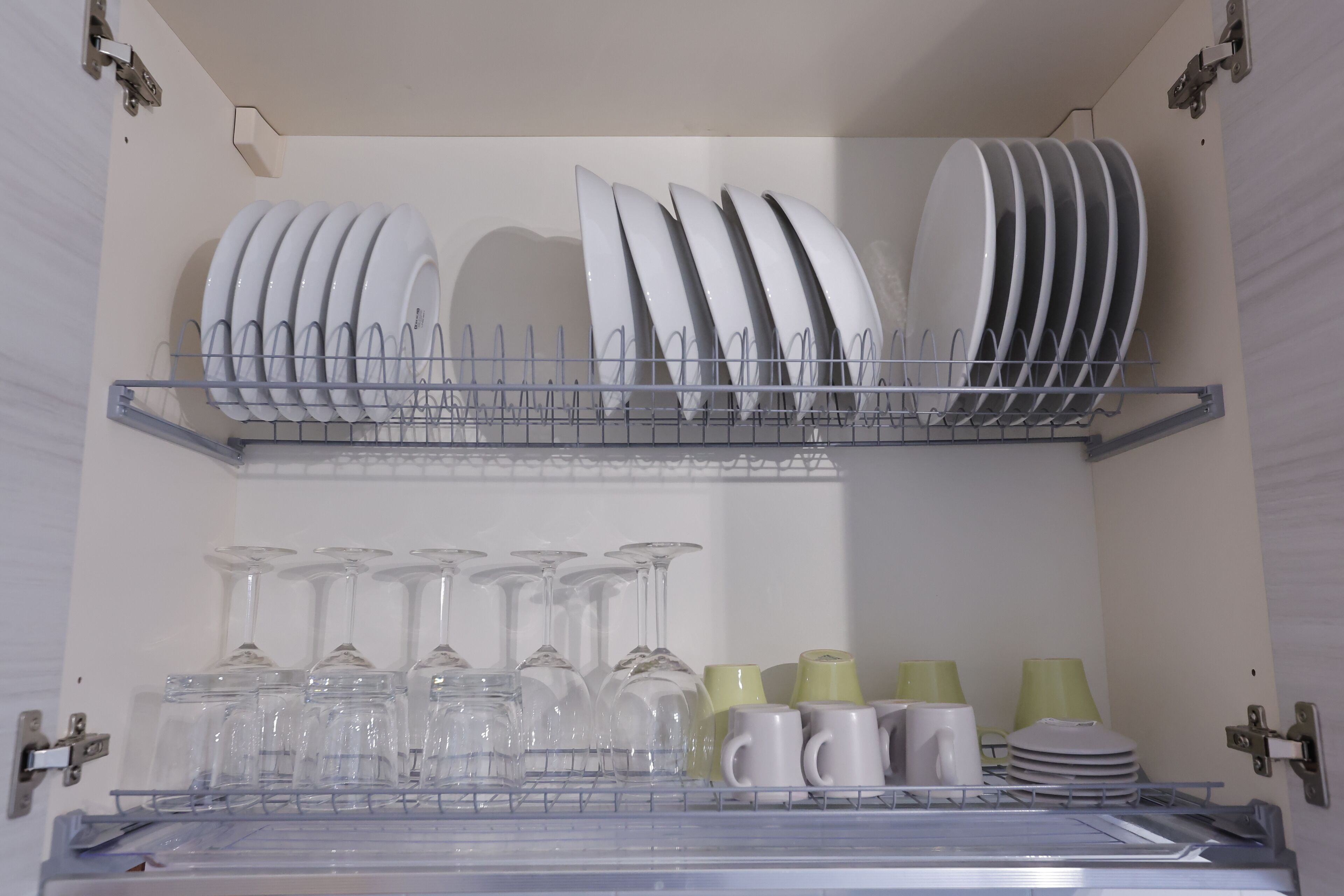 A kitchen with a dish rack holding plates and glasses.
