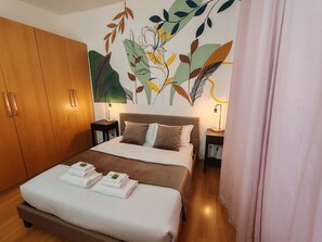 Una cama bien hecha con toallas, un armario amplio y un mural en la pared.