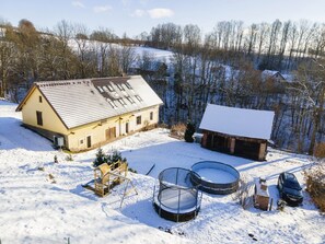 A farmhouse with a sloped roof, a wooden structure with a swing set, and two round water tanks. - Villa in Rudnik With Private hot tub (Rudník)