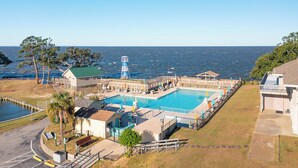 A beachfront property with a large swimming pool, a lighthouse, and a pier. - Canalfront home w/ wraparound decks and community amenities! (Kill Devil Hills)