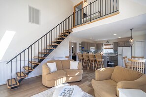 A spacious living area with a staircase, a kitchen, and a dining area. - Canalfront home w/ wraparound decks and community amenities! (Kill Devil Hills)