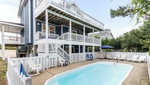 A two-story building with a swimming pool, white railings, and a covered patio area. - Oceanside home in Duck NC with private mini golf course! (Duck)
