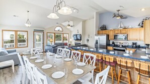 A spacious kitchen with wooden cabinets, a large island, and modern appliances. - Oceanside home in Duck NC with private mini golf course! (Duck)