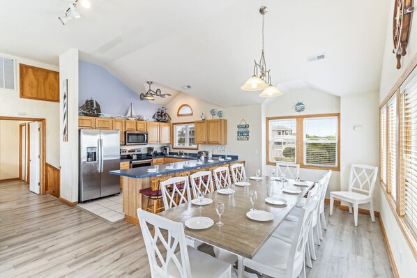A spacious kitchen with wooden cabinets, a stainless steel refrigerator, and a large island with bar stools. - Oceanside home in Duck NC with private mini golf course! (Duck)