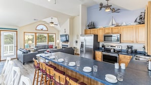 A spacious kitchen with a large island, wooden cabinets, and modern appliances. - Oceanside home in Duck NC with private mini golf course! (Duck)