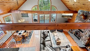 Amplio espacio tipo loft con techo alto, ventanas grandes, chimenea de piedra y una zona de estar acogedora.