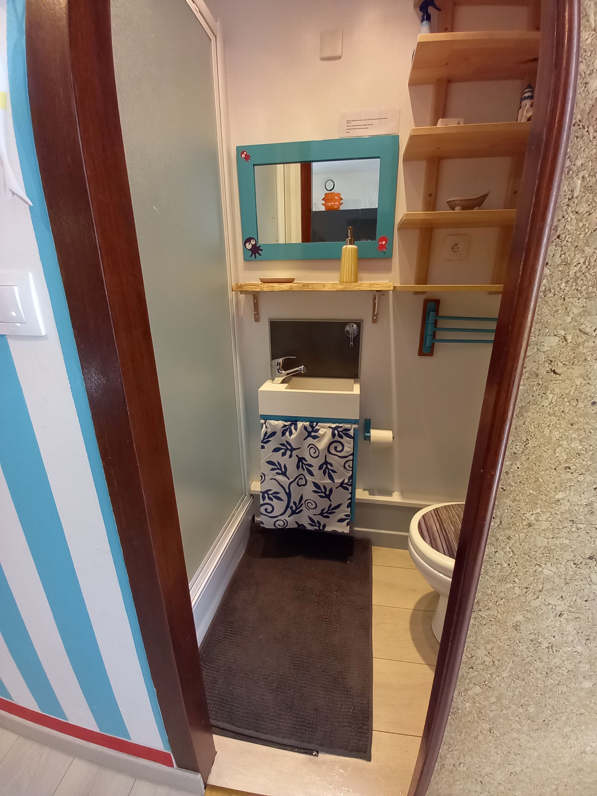 Een badkamer met een wastafel, spiegel en planken.