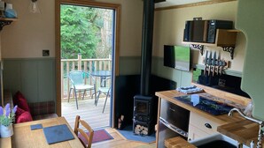 Una cocina acogedora con estufa de leña, comedor con mesa y sillas, y vistas al exterior.