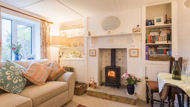 A cozy living room with a sofa, a fireplace, a bookshelf, and a dining area. - Claire's Cottage, Hythe (Hythe)