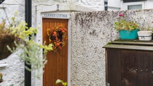 A cottage with a wooden door labeled "CLAIRE'S COTTAGE" and a sign above it. - Claire's Cottage, Hythe (Hythe)