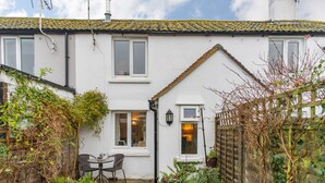 A white house with a tiled roof, a small garden with a table and chairs, and a wooden fence. - Claire's Cottage, Hythe (Hythe)