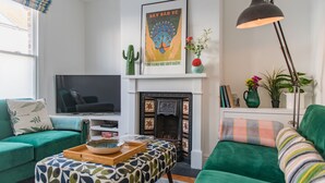 A living room with a television, a fireplace, and green sofas.