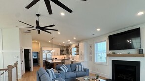 A modern living room with a large sectional sofa, a fireplace, and a ceiling fan.