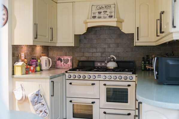 A kitchen with white cabinets, a stove, and a coffee menu sign. - Warwick Villa, Walmer (Walmer)