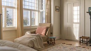 A cozy room with a large window, a chair, a small stool, and a patterned rug. - Warwick Villa, Walmer (Walmer)