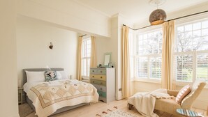 A bedroom with a bed, dresser, chair, and large windows. - Warwick Villa, Walmer (Walmer)