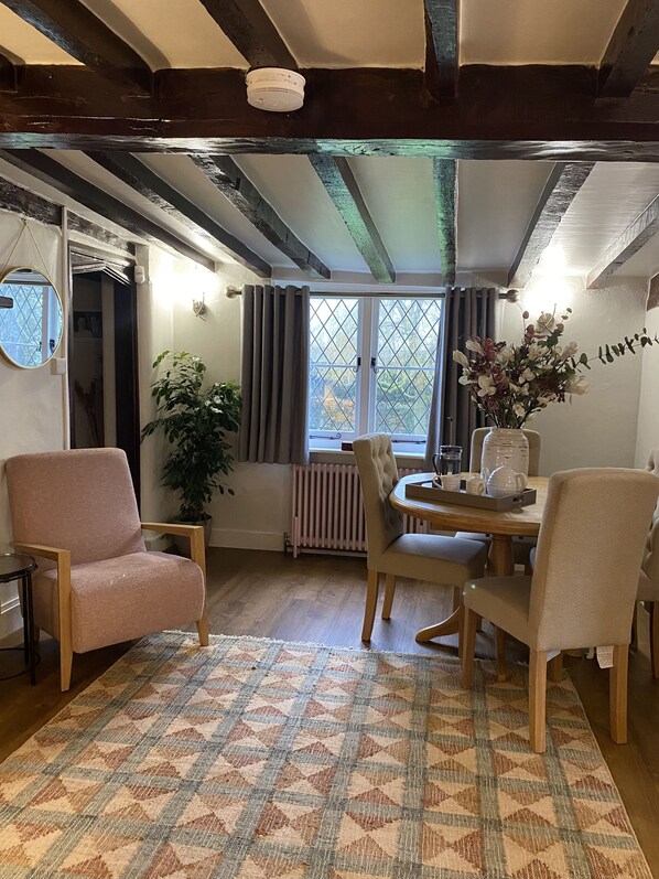 A cozy room with a wooden ceiling, a dining table with chairs, a potted plant, and a radiator.