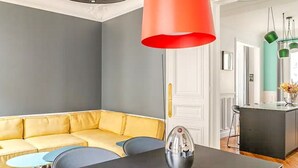 A modern living room with a yellow sofa, a black dining table, and a red pendant light. - Apartment Thorigny - Two Bedroom Villa, Sleeps 6 (Paris)