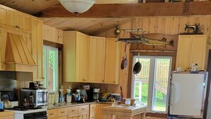 Une cuisine chaleureuse, aménagée dans le style d’un chalet, avec des meubles en bois, une grande table à manger et un coin salon confortable.