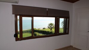 A room with a large window overlooking a beach and ocean.