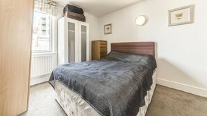 Un dormitorio con cama, armario, cómoda y ventana.