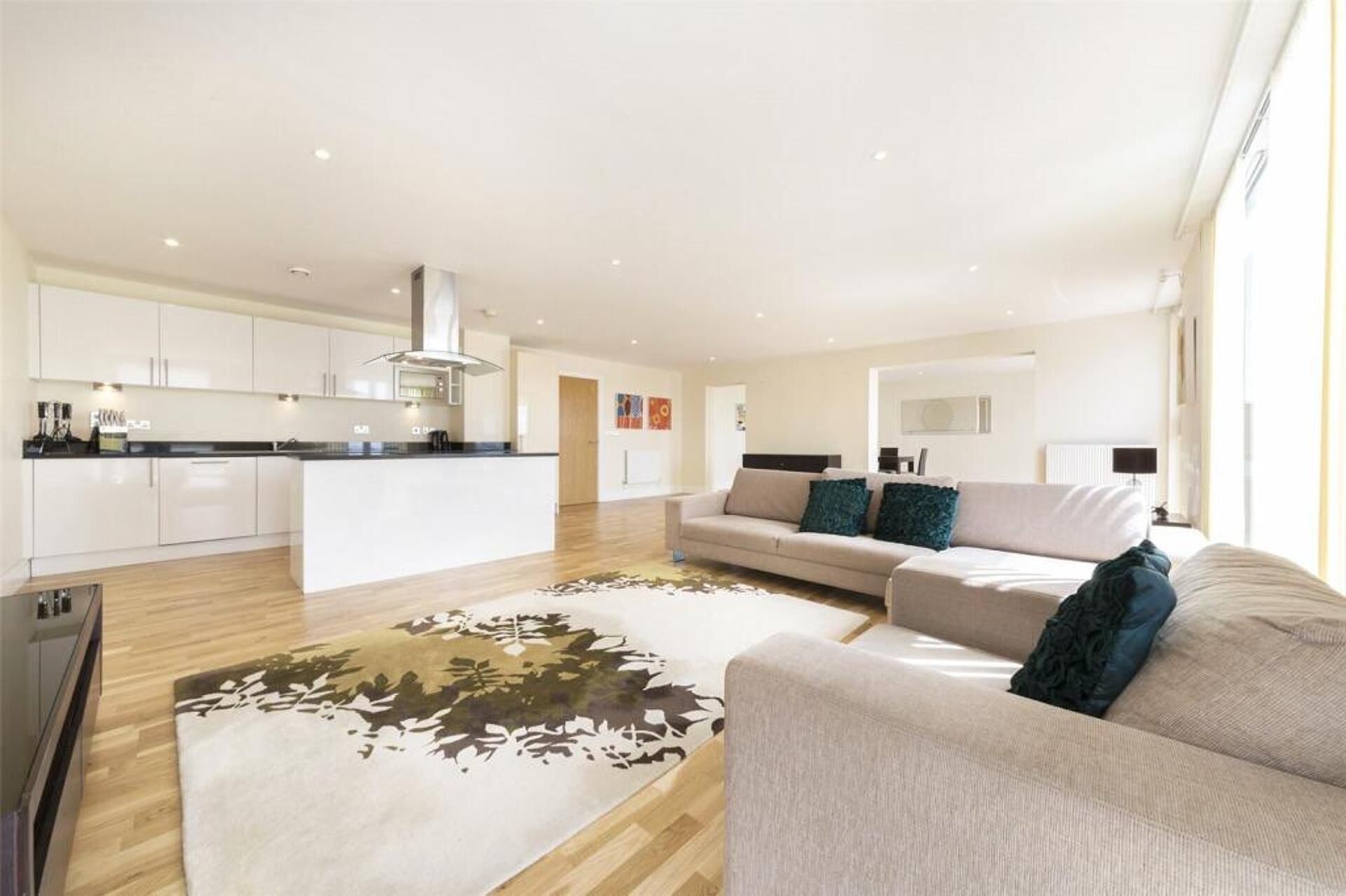 A modern living room with a sofa, a coffee table, and a kitchen in the background.
