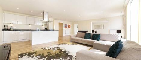 A modern living room with a sofa, a coffee table, and a kitchen in the background.