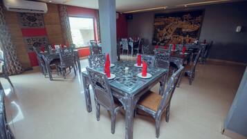 A dining area with multiple tables and chairs, air conditioning units, and a large wall mural.