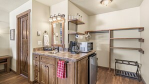 Una cocina con armarios de madera, microondas integrado, cafetera y escurreplatos.