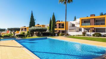 Relax by the pool surrounded by lush greenery and modern buildings.
