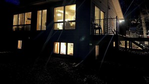 Ein modernes, zweistöckiges Haus mit großen Fenstern, einem Balkon und einem gut beleuchteten Innenraum.