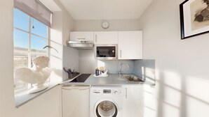 A compact kitchen with a washing machine, a microwave, and a sink.
