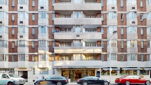 A multi-story building with a central entrance, featuring a sign for Chelsea Cloisters.