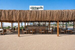 A thatched-roof outdoor seating area with a sign reading 'chiringuito' and wooden tables and chairs. - SUNRISE Alora Aqua Park Resort (Hurghada)