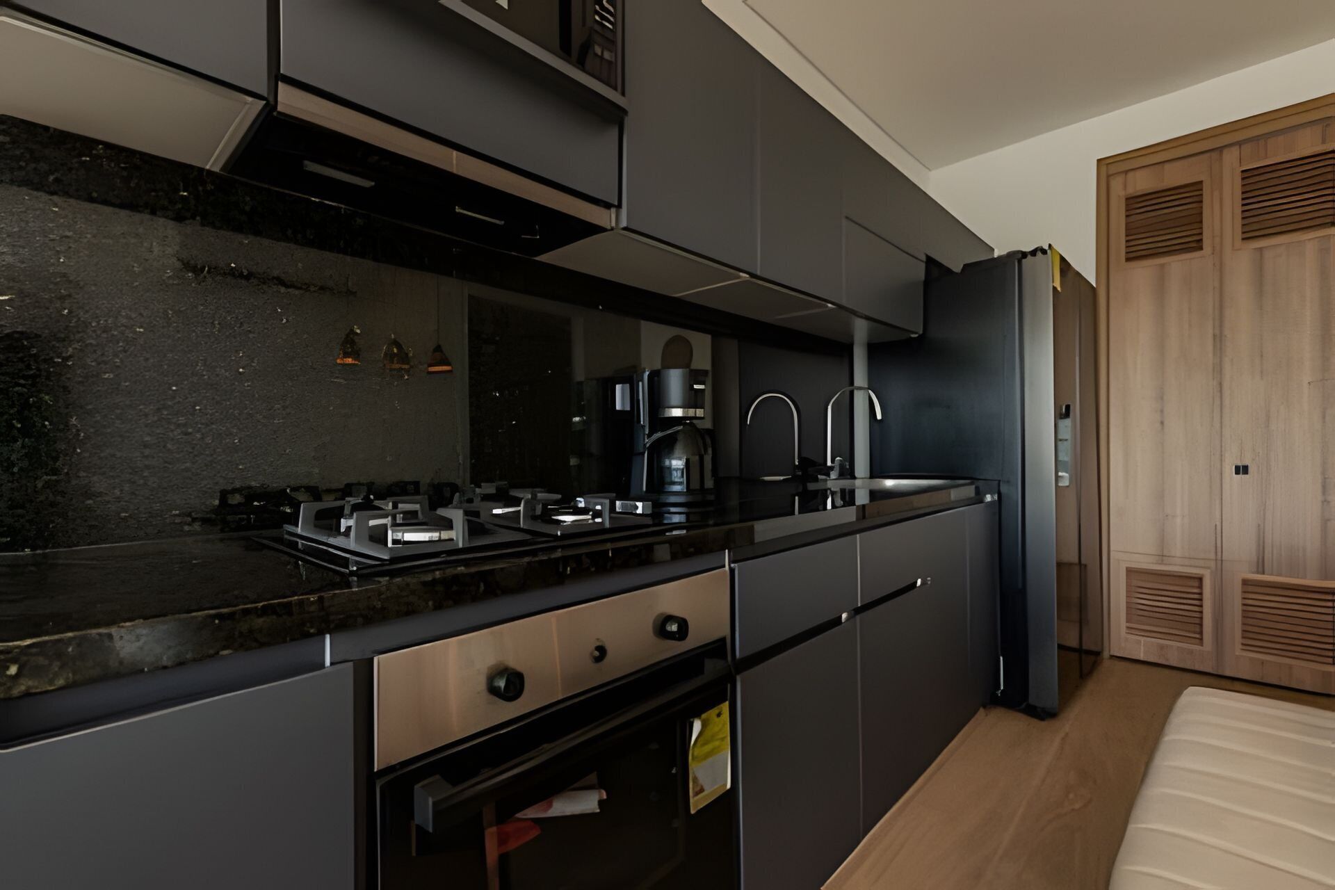 Una cocina moderna con encimera negra, electrodomésticos de acero inoxidable y armarios de madera.