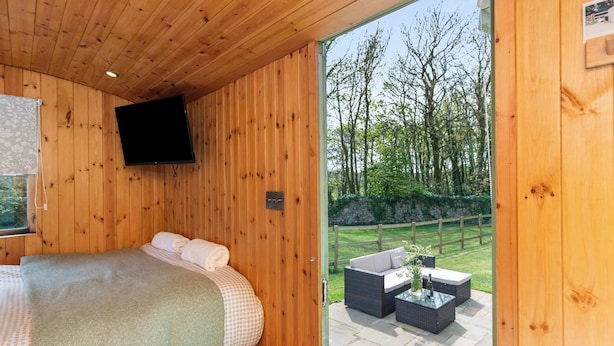 Ein Zimmer mit Holzeinrichtung, einem Bett, einem Fernseher und einer Schiebetür zu einer Außenpatio mit Möbeln.