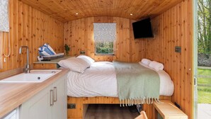 Ein Holzblock-Innenraum mit Bett, Spüle, Fenster und Fernseher.