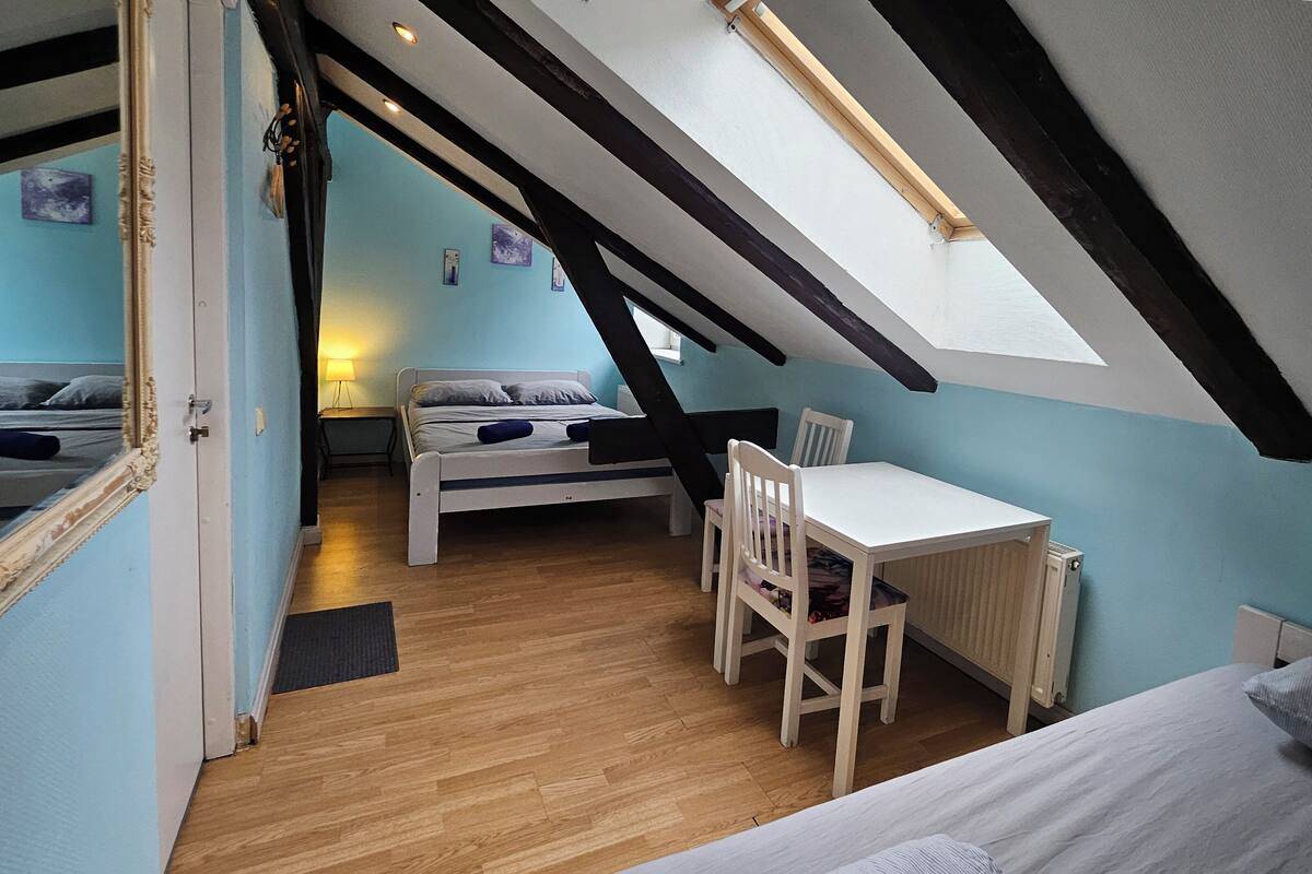A bedroom with a sloped ceiling, a bed, a desk, and a chair.