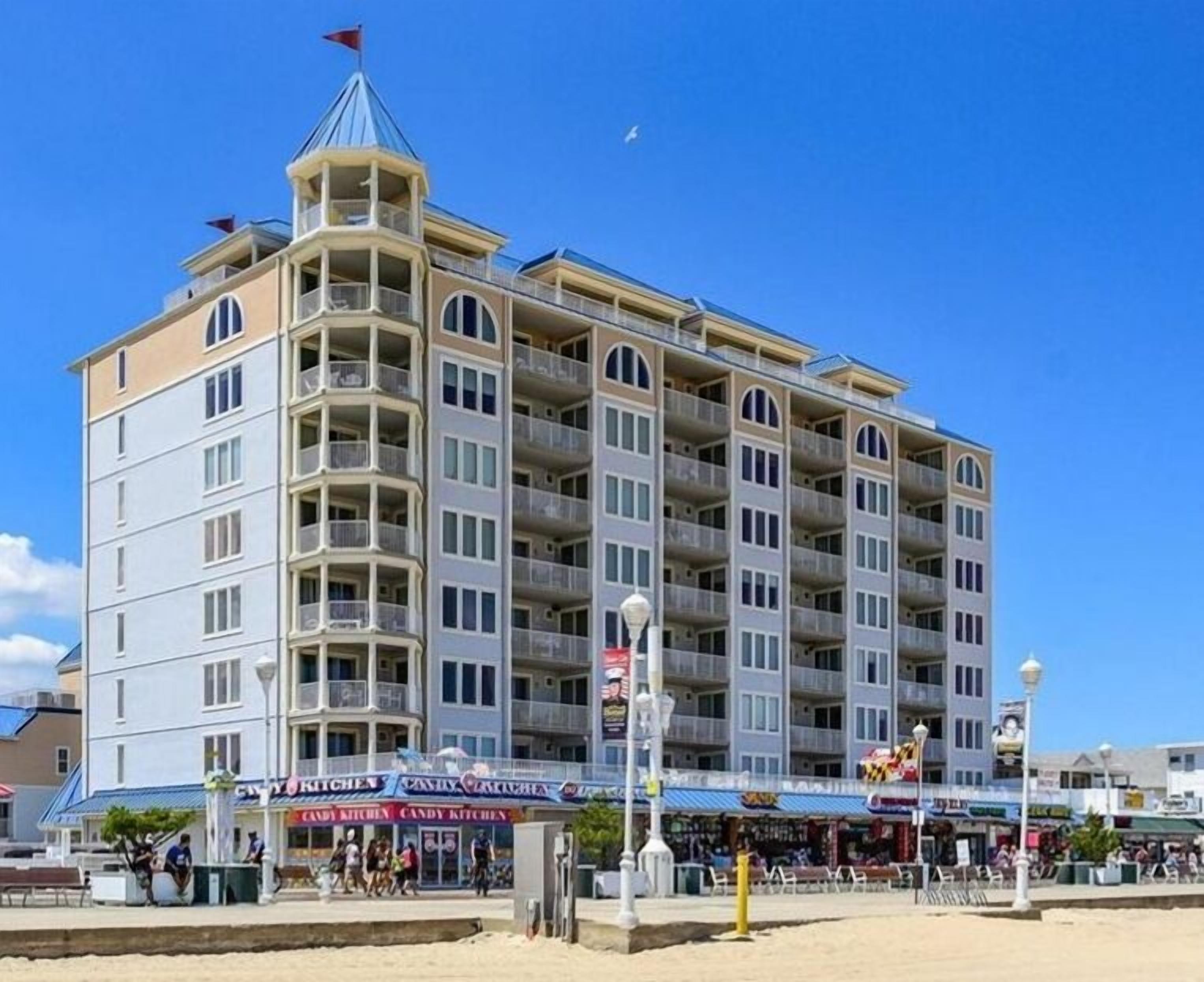A multi-story hotel with balconies, a beachside location, and various shops in front.