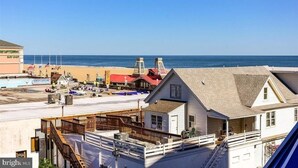 Un edificio frente al mar con balcón, una tienda de surf y una torre de salvavidas.