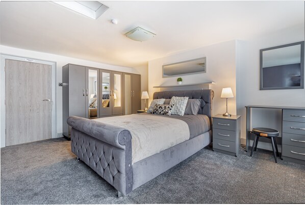 Ein modernes Schlafzimmer mit einem großen Bett, einem Schreibtisch und einem Kleiderschrank.