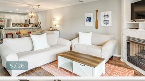 Ein modernes Wohnzimmer mit einer weißen Sofagarnitur, einem Holztisch und einem Kamin.