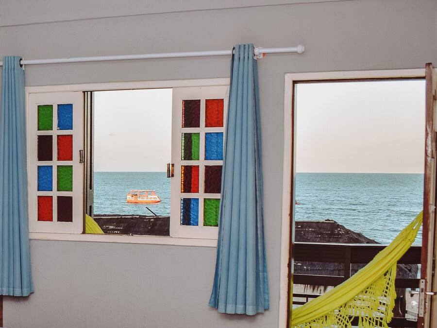 Ett rum med utsikt över havet genom ett fönster med färgglatt glas och blå gardiner.