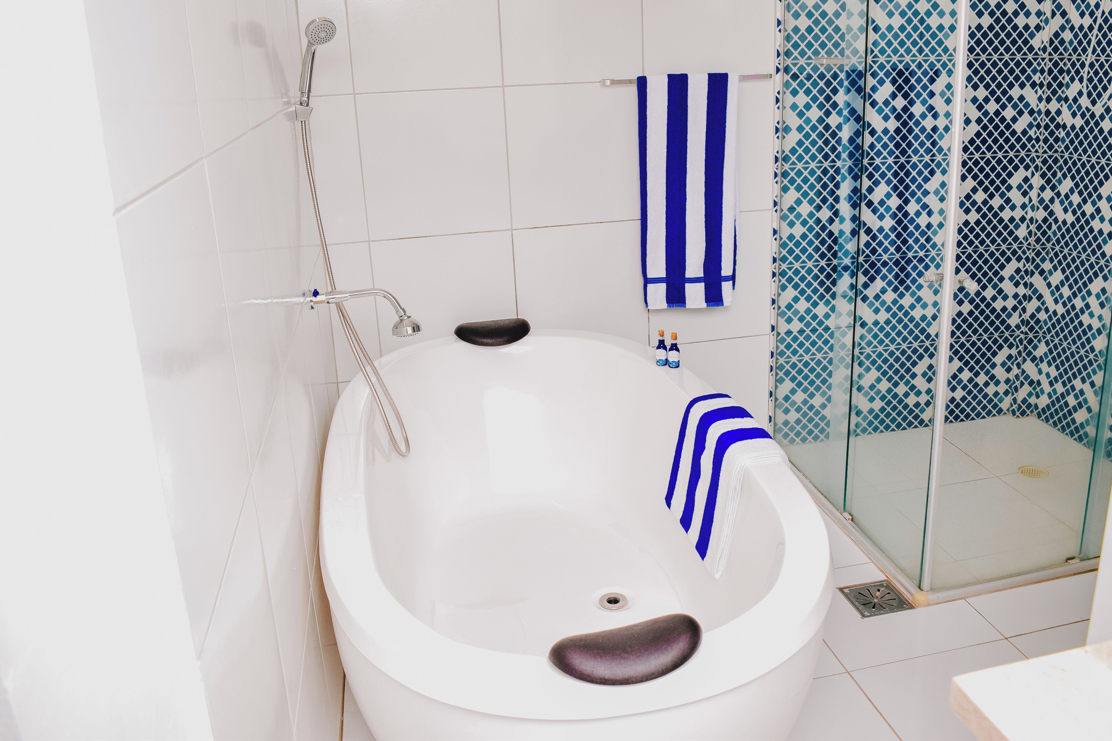 A modern bathroom with a freestanding bathtub, a glass-enclosed shower, and a white tiled floor.