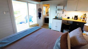 Un dormitorio con cama, almohadas y vistas a una cocina y balcón.