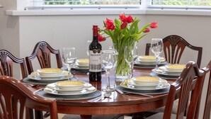 Une table à manger dressée pour six personnes, avec des assiettes, des verres et une bouteille de vin.