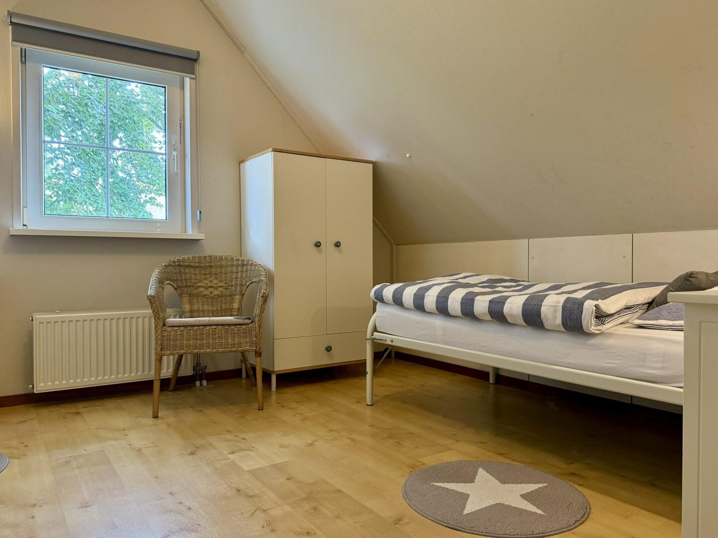 A bedroom with a bunk bed, a wardrobe, a wicker chair, and a radiator.