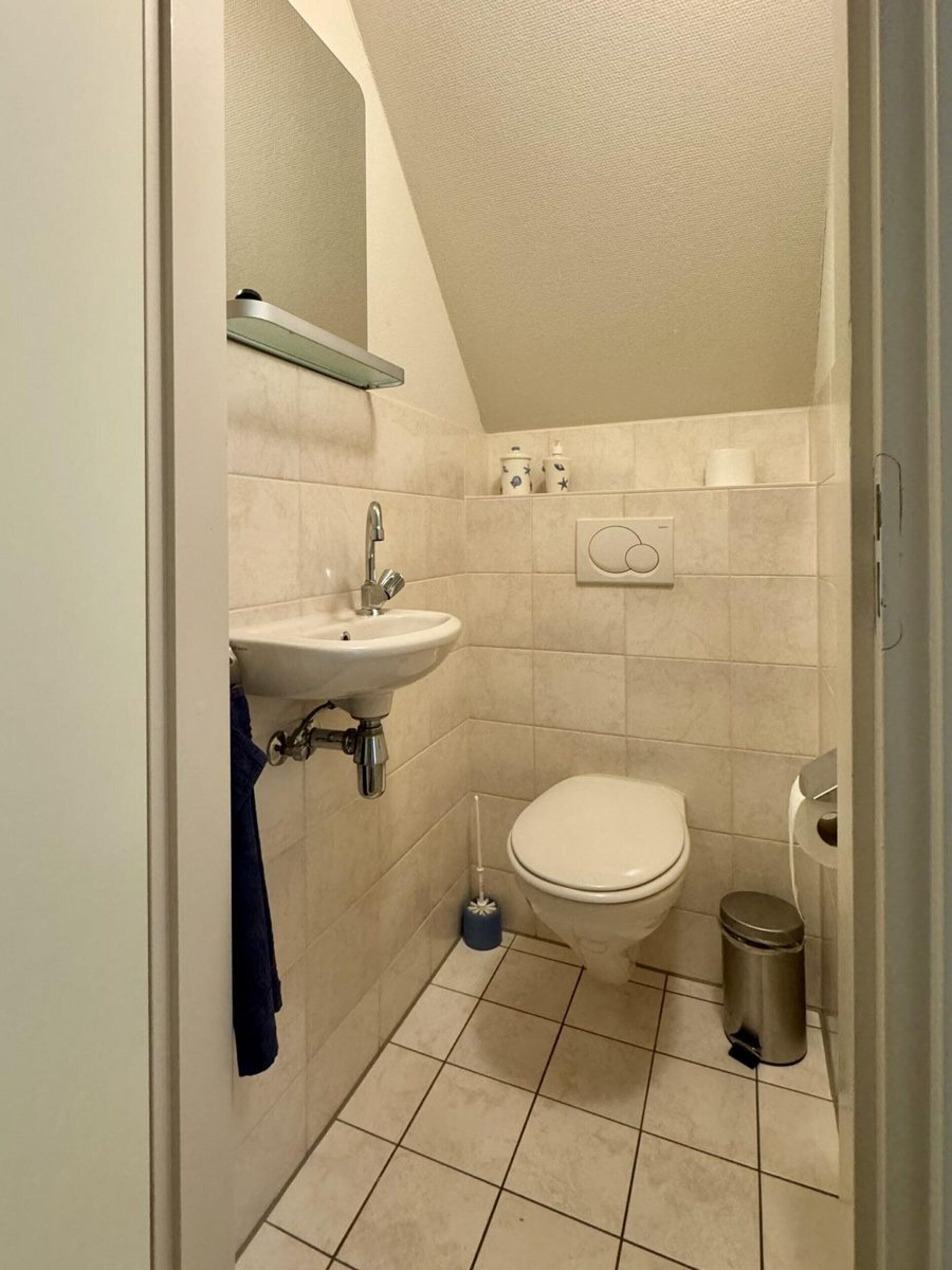 Un baño pequeño y funcional con lavamanos, inodoro y cubo de basura.