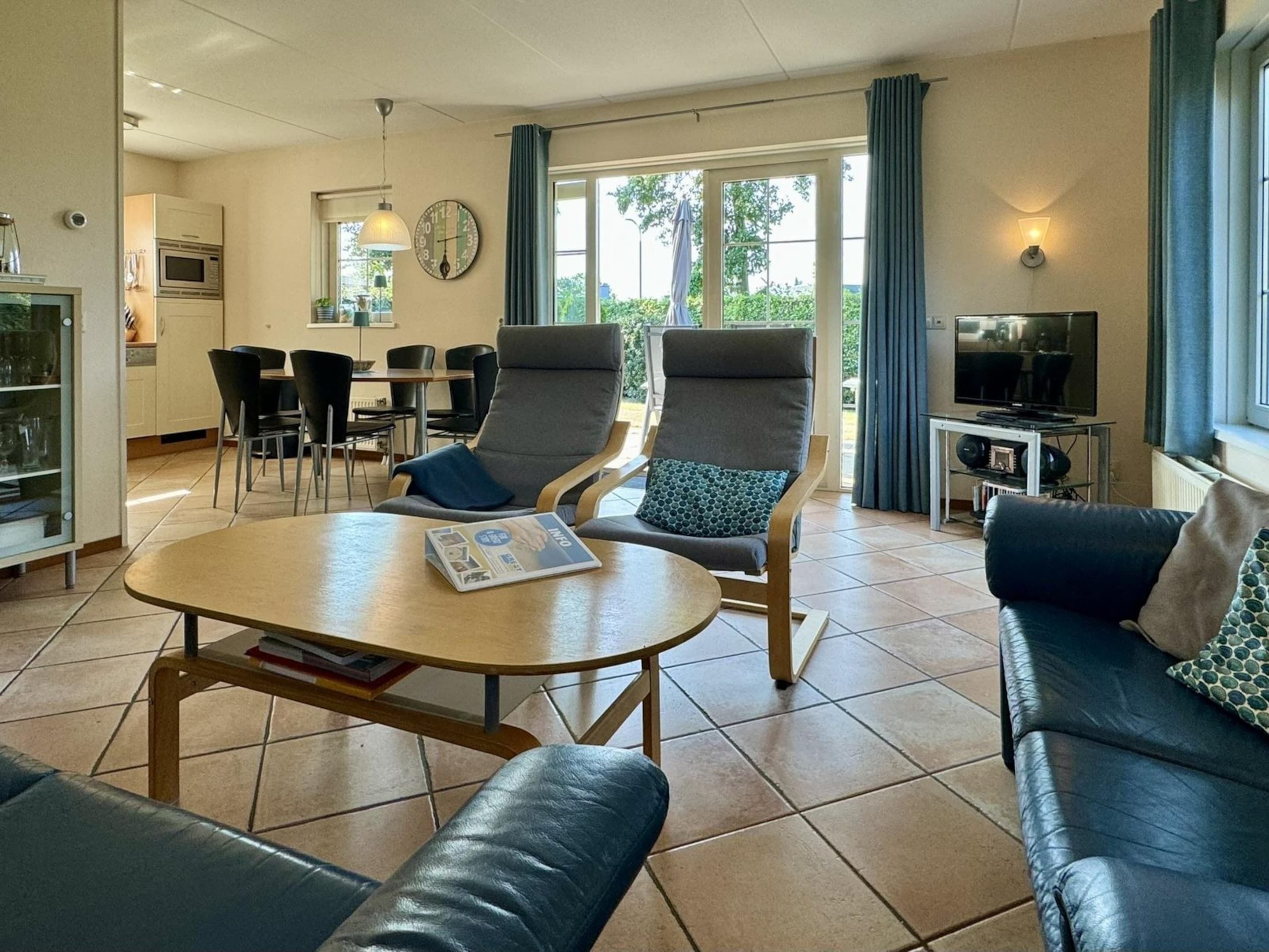 Un salon moderne avec un canapé, une table basse et un téléviseur. Il y a également un coin repas avec des chaises et une table.